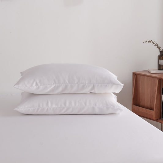 Foto van zijaanzicht van twee kussenslopen Coco White op een bed (kleur wit)